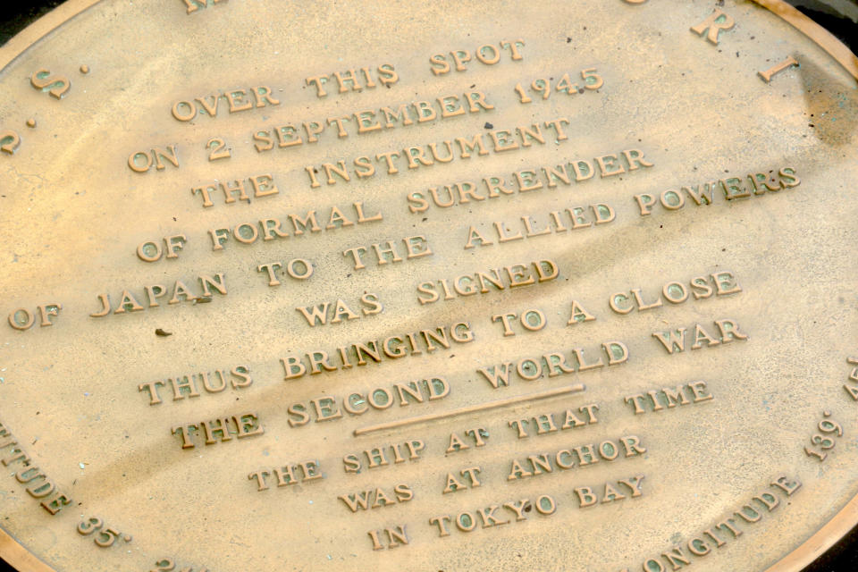 FILE - In this Aug. 11, 2020, file photo, a plaque marks the spot where World War II surrender documents were signed on the USS Missouri Memorial in Pearl Harbor, Hawaii. A Pearl Harbor ceremony in Hawaii marking the 75th anniversary of World War II will only feature veterans living in Hawaii after organizers limited those who can attend over coronavirus concerns. The plan had been to allow about 200 people, mostly WWII veterans, their families and government officials, to gather on the battleship USS Missouri, which hosted the Japanese surrender on Sept. 2, 1945, in Tokyo Bay. (AP Photo/Caleb Jones, File)