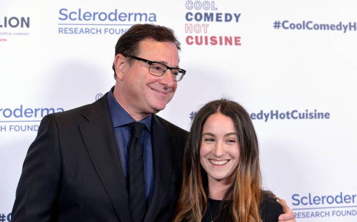 Bob Saget posing for a photo at a red carpet event with his arm around his daughter's shoulders