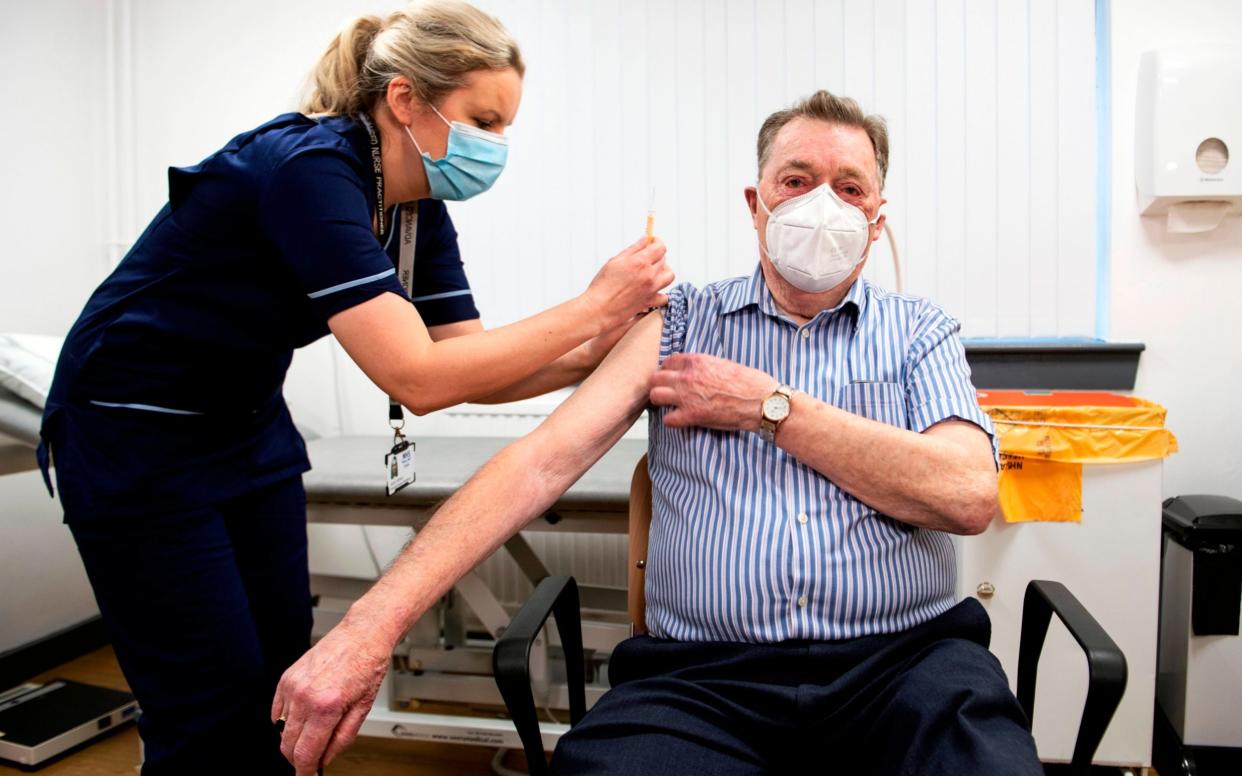 Advanced nurse practitioner Justine Williams (L) prepares to administer a dose of the AstraZeneca/Oxford Covid-19 vaccine to 82-year-old James Shaw, the first person in Scotland to receive the vaccination - AFP