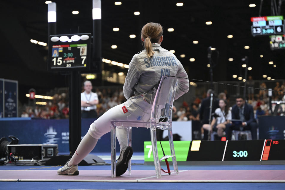 FILE - Russian competing as a neutral athlete Anna Smirnova remains seated after her bout with Ukraine's Olga Kharlan in the women's individual sabre best of 64 round match at the World Fencing Championship in Milan, Italy, on July 27, 2023. With just six months to go until the Paris Olympics, it’s still not clear if Russians will be competing and, if so, how many. Russians are qualifying for Olympic spots as “neutral athletes” in combat events such as judo and wrestling. They are not yet in some of the Games’ highest-profile events like track and field, swimming and gymnastics. (Tibor Illye/MTI via AP, File)