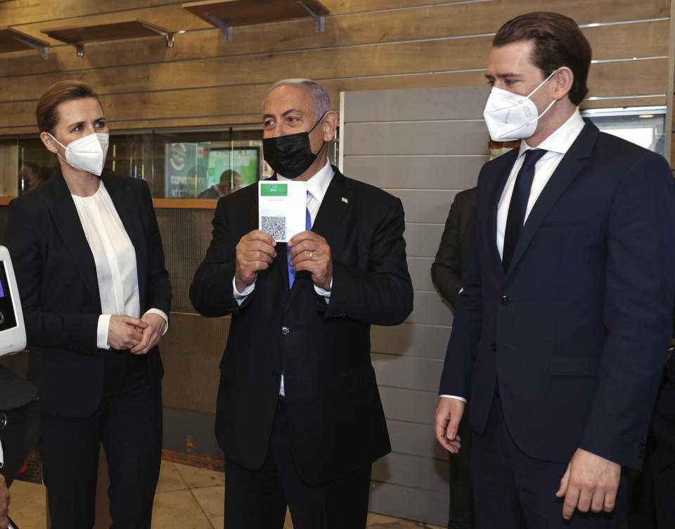 Israeli Prime Minister Benjamin Netanyahu, center, holds a "Green Pass," for citizens vaccinated against COVID-19, as he visits a fitness gym with Austrian Chancellor Sebastian Kurz, right, and Danish Prime Minister Mette Frederiksen, to observe how the pass is used, in Modi'in, Israel, Thursday, March 4, 2021. Frederiksen and Kurz are on a short visit to Israel for to pursue the possibilities for closer cooperation on COVID-19 and vaccines. (Avigail Uzi/Pool via AP)