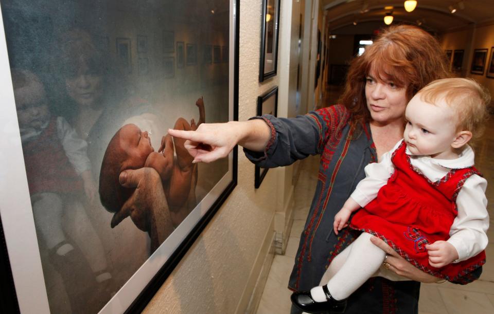 The Oklahoman Features Writer Brandy McDonnell's 20-month-old daughter Brenna Faire McDonnell and OKC photographer M.J. Alexander look at Brenna's portrait as a newborn March 21, 2012, at the state Capitol's North Gallery. As part of Alexander's photography book and exhibit “Portrait of a Generation — The Children of Oklahoma: Sons and Daughters of the Red Earth," Brenna's baby portrait has been exhibited around the state, as well as in London over the past 13 years.