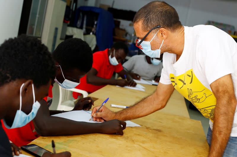 Tito Martin gives a lesson of Spanish in his private garage to migrants who have arrived on the island by boat, in Las Palmas