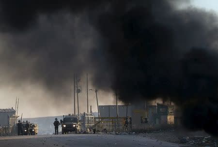 Smoke rises from burning tyres as Israeli troops take position during clashes with Palestinian protesters, near Israel's Ofer Prison near the West Bank city of Ramallah December 25, 2015. REUTERS/Mohamad Torokman