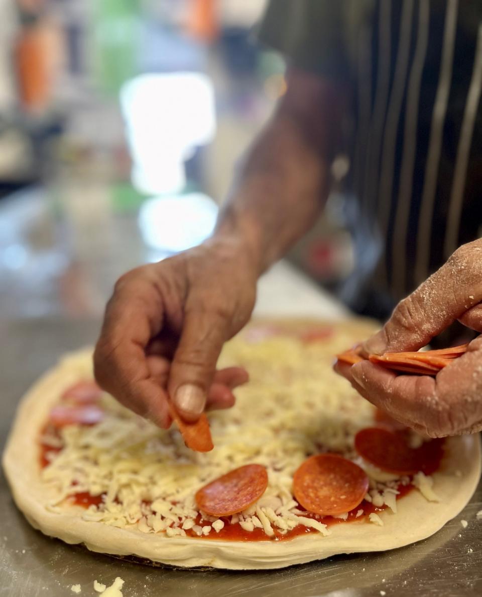 Tony's New York Pizza & Pasta owner Tony Madkour adds pepperoni to a pizza.