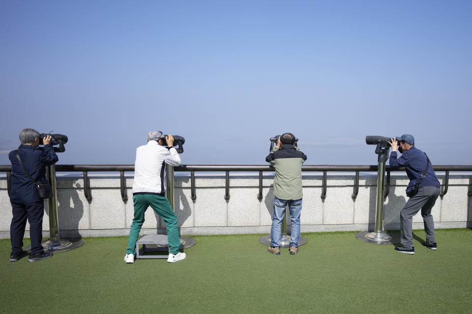 Visitors use binoculars to see the North Korean side from the unification observatory in Paju, South Korea, Wednesday, April 19, 2023. North Korean leader Kim Jong Un said his country has completed the development of its first military spy satellite and ordered officials to go ahead with its launch as planned, state media reported Wednesday. (AP Photo/Lee Jin-man)