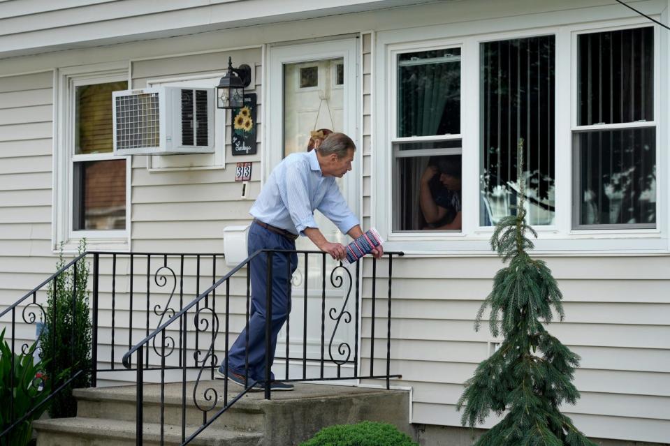 Senate President Dominick Ruggerio talks with a homeowner through her front window while campaigning in North Providence in July 2022.