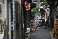 A man wearing a protective mask to help curb the spread of the coronavirus walks along an empty bar street Tuesday, June 22, 2021, in Tokyo. The Japanese capital confirmed more than 430 new coronavirus cases on Tuesday. (AP Photo/Eugene Hoshiko)