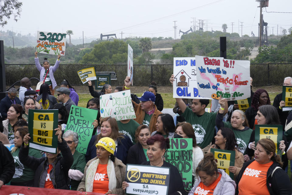 Members of Campaign for a Safe and Healthy California coalition campaign for Keep The Law (SB 1137) in Inglewood, Calif., on Friday, March. 22, 2024. In the background, is the Inglewood Oil Field, which covers around 1,000 acres making it one of the largest contiguous urban oil fields in the United States. The law, if upheld, would require all oil or gas production facilities or wells within a health protection zone to comply with new regulations. (AP Photo/Damian Dovarganes)