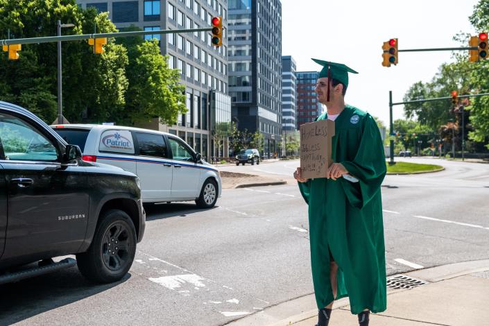 Michael Wilson, a recent MSU graduate, stands at Michigan and Grand River Avenues on May 15, 2023, hoping to raise money for housing and his phone plan.