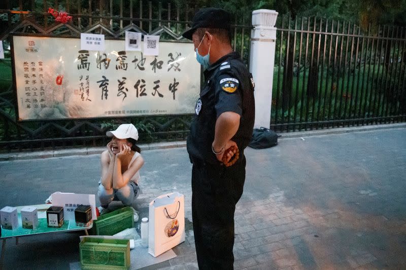 A city law enforcement officer orders street vendor Yan Ying to pack up her her stall following an outbreak of the coronavirus disease (COVID-19) in Beijing