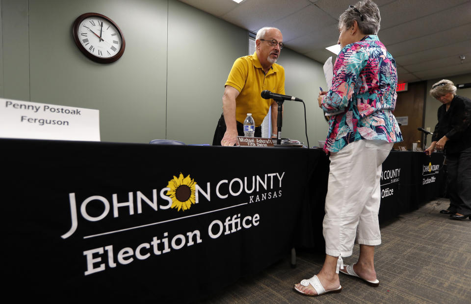 Board of County Commissioners 1st District Commissioner Ron Shaffer, left, talks with Barbara Holzmark, of Leawood, Kan., following the Johnson County Board of Canvassers meeting, Monday, Aug. 13, 2018, in Olathe, Kan. County election officials across Kansas on Monday began deciding which provisional ballots from last week's primary election will count toward the final official vote totals, with possibility that they could create a new leader in the hotly contested Republican race for governor. Secretary of State Kris Kobach led Gov. Jeff Colyer by a mere 110 votes out of more than 313,000 cast as of Friday evening. (AP Photo/Charlie Neibergall)