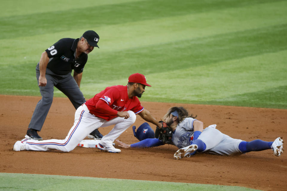 Umpire Rob Drake (30) watches as Texas Rangers second baseman Marcus Semien tags out Toronto Blue Jays' Bo Bichette on an attempted steal during the first inning of a baseball game Friday, Sept, 9, 2022, in Arlington, Texas. (AP Photo/Michael Ainsworth)