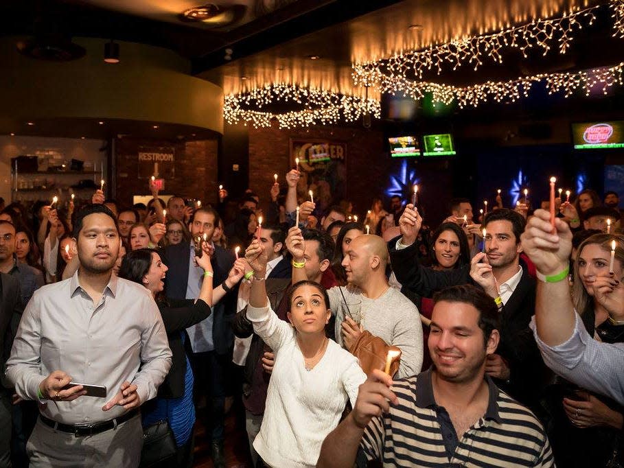 A group of people hold candles at a party.