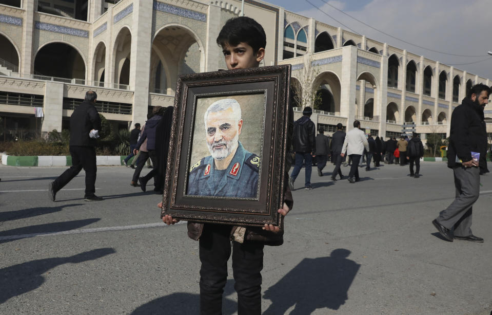 A boy carries a portrait of Iranian Revolutionary Guard Gen. Qassem Soleimani, who was killed in a U.S. airstrike in Iraq, prior to the Friday prayers in Tehran, Iran, Friday Jan. 3, 2020. Iran has vowed "harsh retaliation" for the U.S. airstrike near Baghdad's airport that killed Tehran's top general and the architect of its interventions across the Middle East, as tensions soared in the wake of the targeted killing. (AP Photo/Vahid Salemi)