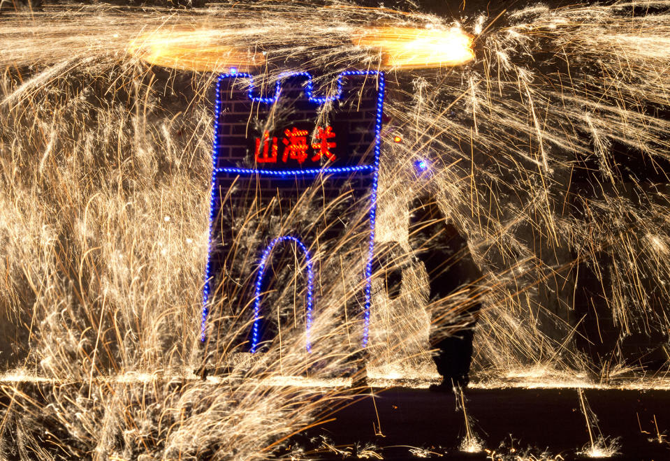 A performer at the Great Wall Iron Sparks show turns a mechanism to spin molten iron and create sparks in Yanqing county on the outskirts of Beijing, China, Saturday, Jan. 28, 2017. An ancient craft that can be traced back several hundred years, the company is trying to revive the practice of throwing the molten iron and using the Lunar New Year period to showcase their latest choreography. Chinese character reads 