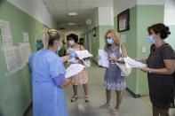 A medical worker distributes papers to teachers and school staff waiting for a blood COVID-19 test at the San Carlo Hospital in Milan, Italy, Wednesday, Aug. 26, 2020. Despite a spike in coronavirus infections, authorities in Europe are determined to send children back to school. Italy, Europe’s first virus hot spot, is hiring 40,000 more temporary teachers and ordering extra desks, but some won’t be ready until October. (AP Photo/Luca Bruno)