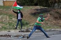 A Palestinian protester uses a sling to hurl stones at Israeli troops during clashes at Hawara checkpoint near the West Bank city of Nablus November 28, 2015. REUTERS/Ahmad Talat