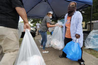 Emily Dragoo, center, a teacher at Apollo Jr. High hands out food to Richardson Independent School District families at a distribution site in Dallas, Friday, May 15, 2020. Approximately 250 bags of food were handed out at this location Friday. Each bag contains two days worth of lunch and breakfast items. (AP Photo/Tony Gutierrez)