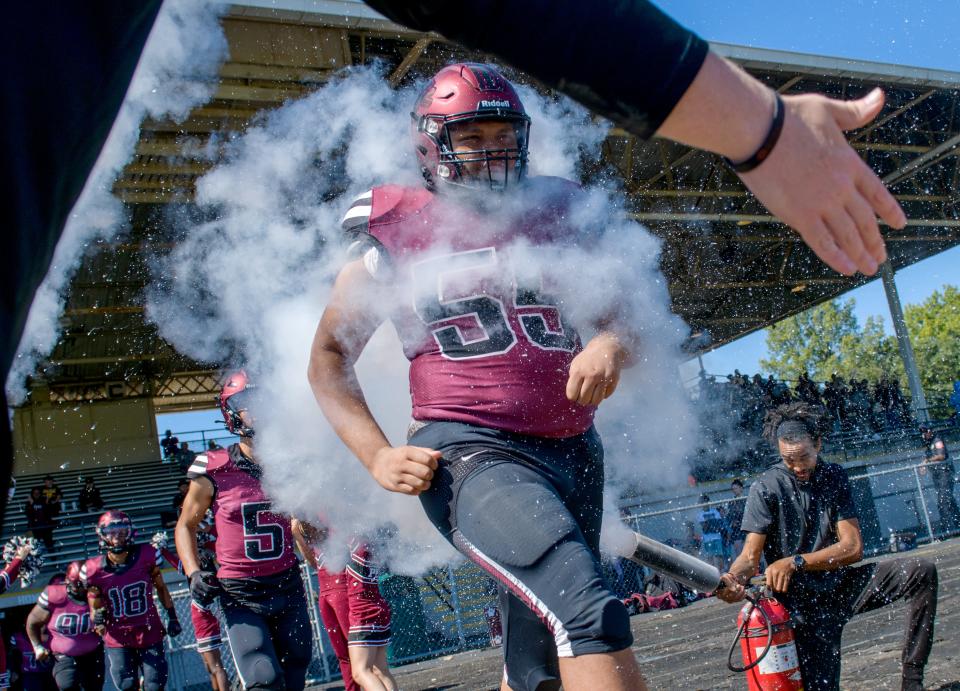 Peoria's Jamere Fuller (55) and his teammates run through mist created by fire extinguishers as they take the field against Manual on Saturday, Sept. 24, 2022 at Peoria Stadium.
