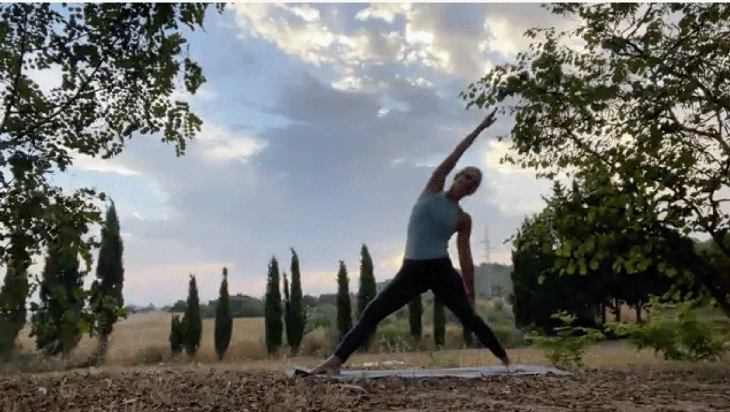 Woman practicing yoga outside at sunrise in a side stretch