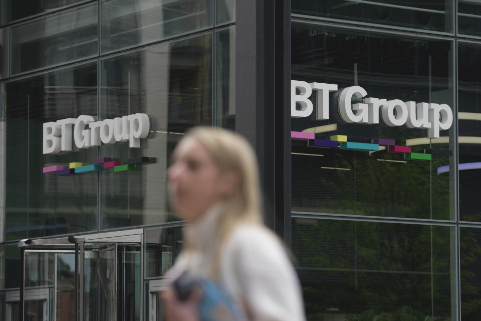 A woman walks in front of the BT headquarters, in London, Thursday, May 18, 2023. U.K. telecom company BT Group said Thursday that it plans to shed up to 55,000 jobs by the end of the decade as part of an overhaul aimed at slimming down its workforce to slash costs. (AP Photo/Kin Cheung)