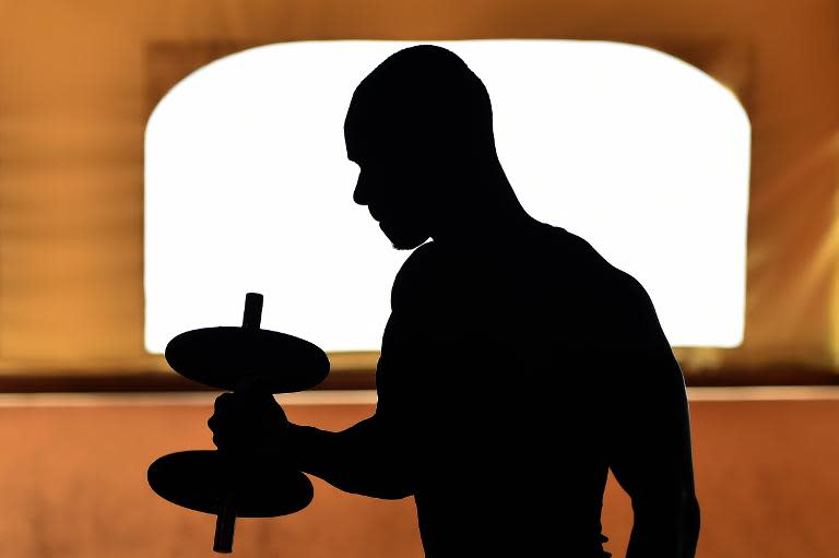 Ebou Cham, a 21-year-old asylum seeker from Gambia, trains with weights at the hotel Villa Mokarta, temporarily transformed in a center for immigrants, in Salemi, Sicily, on October 21, 2014