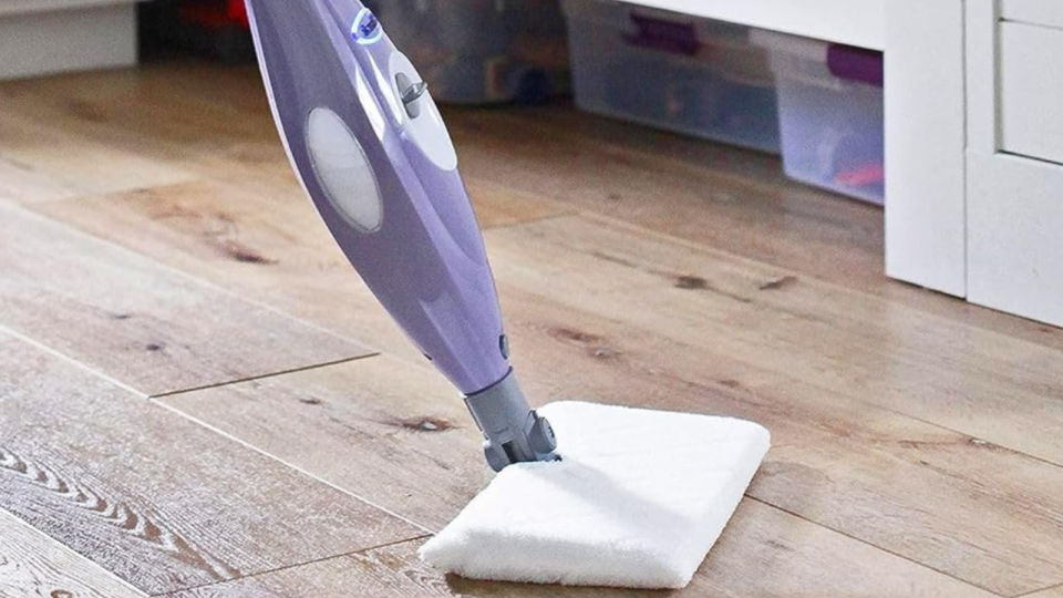 the purple Shark steam mop being used to clean a wood floor