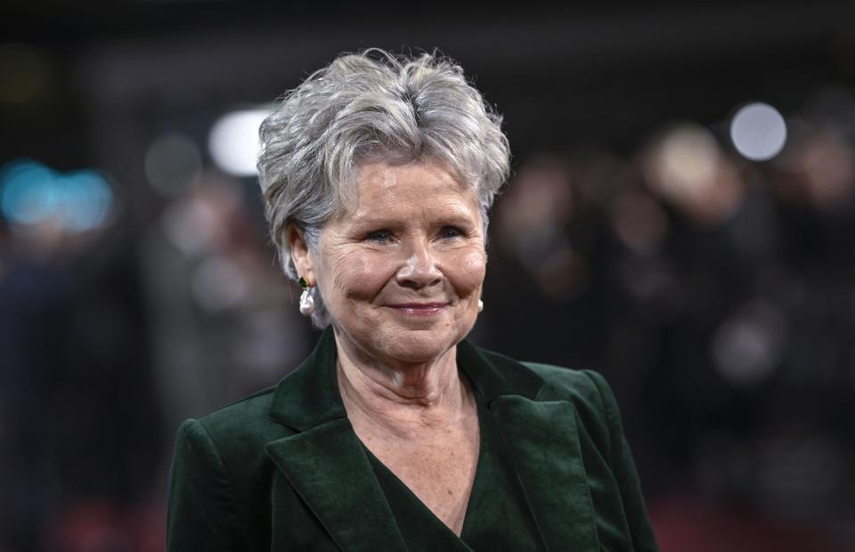 imelda staunton, wearing a green suit, smiles as she attends a red carpet event