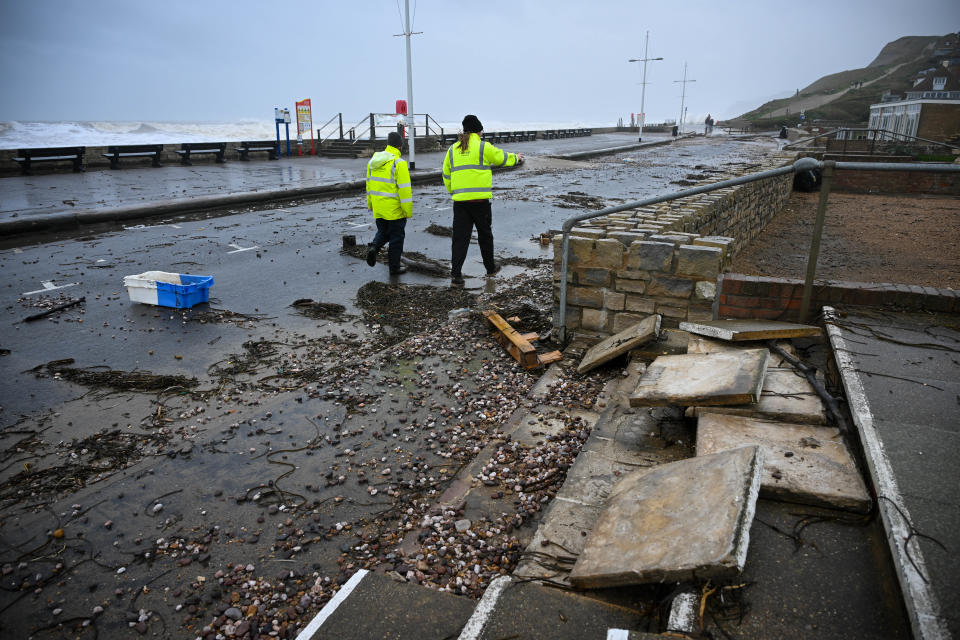Council workers walk past damage and debris on the road in West Bay, Dorset (Getty Images)