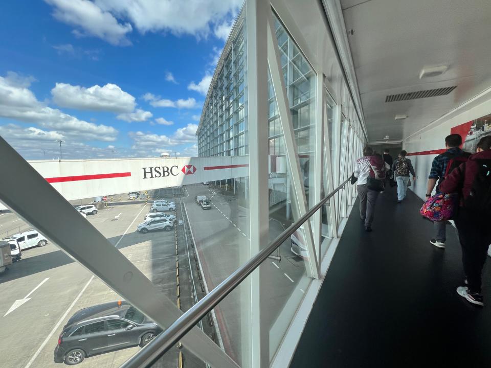 Passengers walk down a long jet bridge at London Heathrow Airport