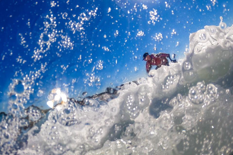 Water and sea foam blur the profile of a man as he rides a wave.