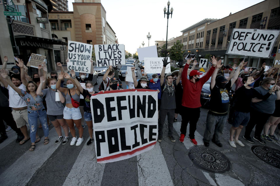 Demonstrators hold signs in the Country Club Plaza district of Kansas City, Mo. Saturday, June 13, 2020, as they protest the death of George Floyd who died after being restrained by Minneapolis police officers on May 25. (AP Photo/Charlie Riedel)