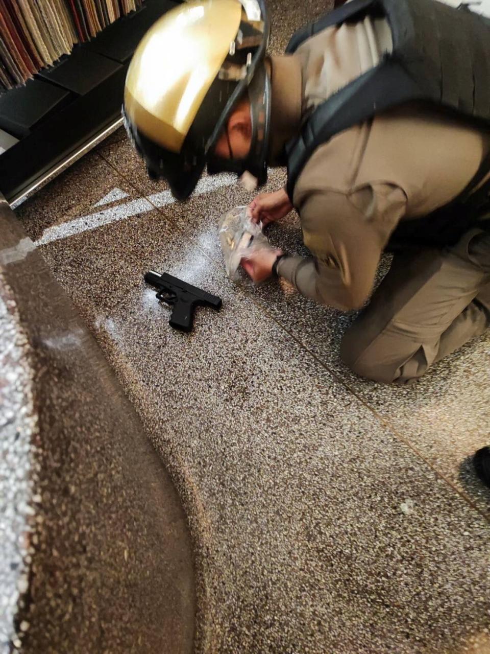 A police officer collects a gun following shots fired at the luxury Siam Paragon shopping mall, in Bangkok (Reuters)