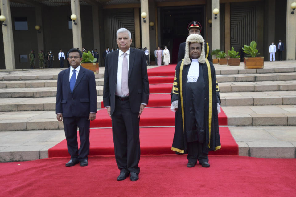 FILE - In this photo provided by Sri Lankan President's Office, Sri Lanka's newly elected president Ranil Wickremesinghe, flanked by Parliament General Secretary Dhammika Dasanayake, left, and Parliament Speaker Mahinda Yapa Abeywardana, stands for national anthem during his swearing-in ceremony in Colombo, Sri Lanka, Thursday, July 21, 2022. On Friday, Wickremesinghe appointed a classmate and ally of ousted President Gotabaya Rajapaksa to be his prime minister and partner in rescuing the country from its predicament. The question is whether they can muster the political heft and enough support from a public fed up with shortages of food, fuel and medicine to get the job done. (Sri Lankan President's Office via AP, File)