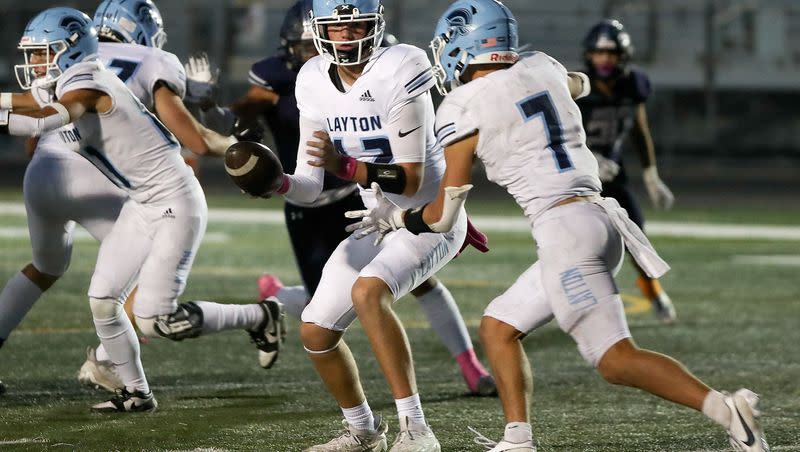 Layton quarterback Madden Sargent hands the ball to Layton’s Ryan Wensel during the first round of 6A football playoffs against Copper Hills at Copper Hills in West Jordan on Friday, Oct. 20, 2023. Layton won 24-20.