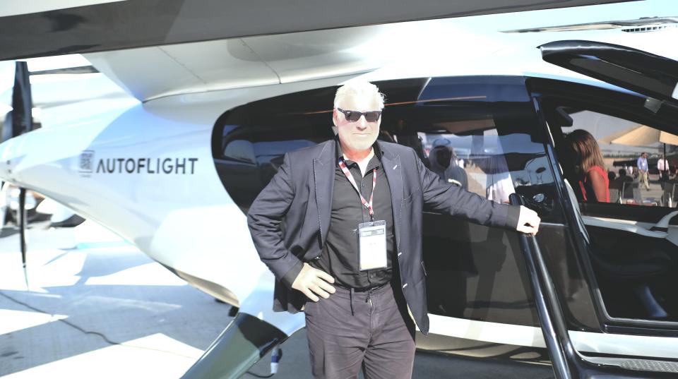 Frank Stephenson wears a black suit and poses in front of AutoFlight's Prosperity I