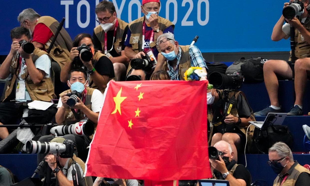 <span>A Chinese flag is unfurled on the podium of a swimming event final at the Tokyo Olympics.</span><span>Photograph: Charlie Riedel/AP</span>