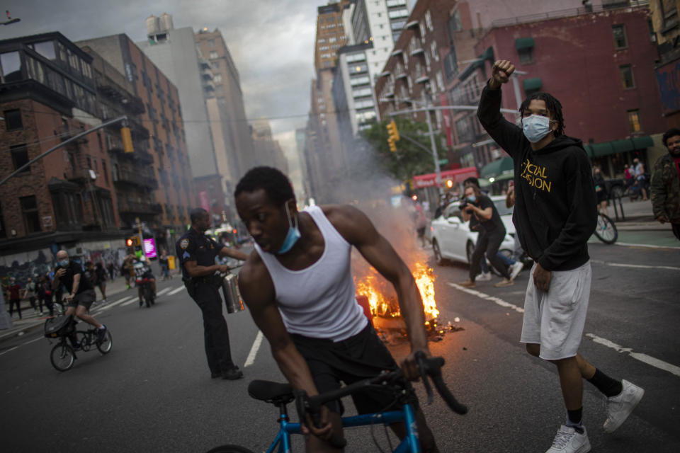 Protesters march down the street as trash burns in the background during a solidarity rally for George Floyd, Saturday, May 30, 2020, in New York. Protests were held throughout the city over the death of George Floyd, a black man who died after being restrained by Minneapolis police officers on May 25. (AP Photo/Wong Maye-E)