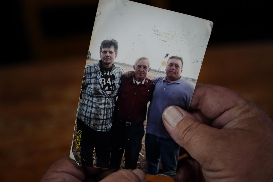 Daniel Guess holds a photograph of himself, right, along with his father, Larry Guess, center, and brother David Guess, left, on Thursday, June 23, 2022, in Athens, Ala. David Guess, 51, was killed by gun violence in March. Guess’ death began with an argument over a car part. (AP Photo/Brynn Anderson)