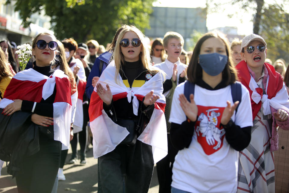 Women wearing old Belarusian national flags attend an opposition rally to protest the official presidential election results in Minsk, Belarus, Saturday, Sept. 19, 2020. Daily protests calling for the authoritarian president's resignation are now in their second month and opposition determination appears strong despite the detention of protest leaders. (AP Photo/TUT.by)