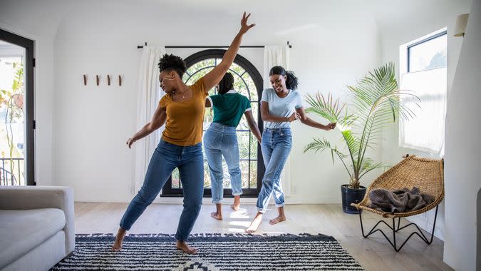 Women friends having fun at home dancing and singing in the living room of their Los Angeles apartment.