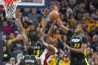 Indiana Pacers center Myles Turner (33) and forward Aaron Nesmith (23) attempt to block a shot by Miami Heat forward Jimmy Butler, center, during the second half of an NBA basketball game in Indianapolis, Sunday, April 7, 2024. (AP Photo/Doug McSchooler)