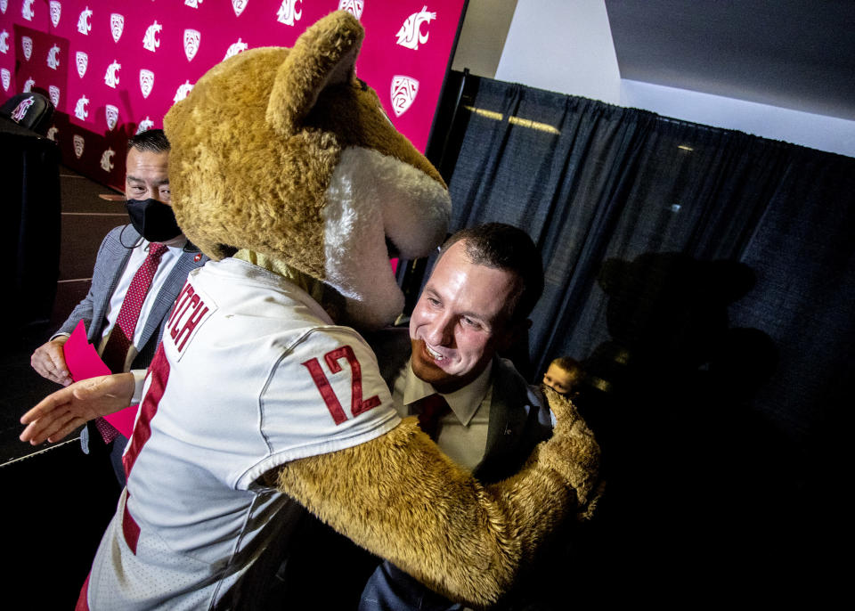 New Washington State football coach Jake Dickert hugs school mascot Butch after a news conference Thursday, Dec. 2, 2021, in Pullman, Wash. Dickert was elevated last week from interim coach after the Cougars pounded rival Washington 40-13 in the annual Apple Cup game in Seattle. (August Frank/Lewiston Tribune via AP)