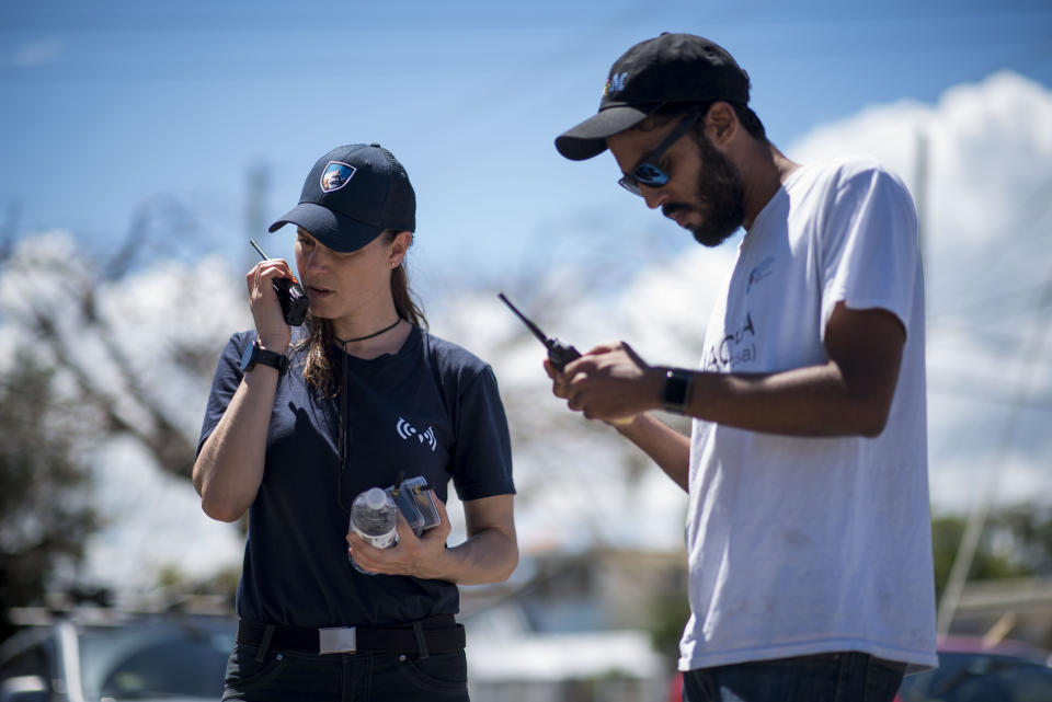 In this March 13, 2019 photo, self-taught Puerto Rican tech developer Pedro Cruz, right, and Maria M., test the Clusterduck system, that provides a low-frequency Wi-Fi connection, in Isabela, Puerto Rico. Cruz envisions before a storm giving people 5-foot-long mats with standardized symbols indicating needs - such as food, water or medical care - that could be spread out on flat surfaces. Programmed drones could fly overhead, read the symbols and process them into data about needs and locations for emergency responders. (AP Photo/Carlos Giusti)