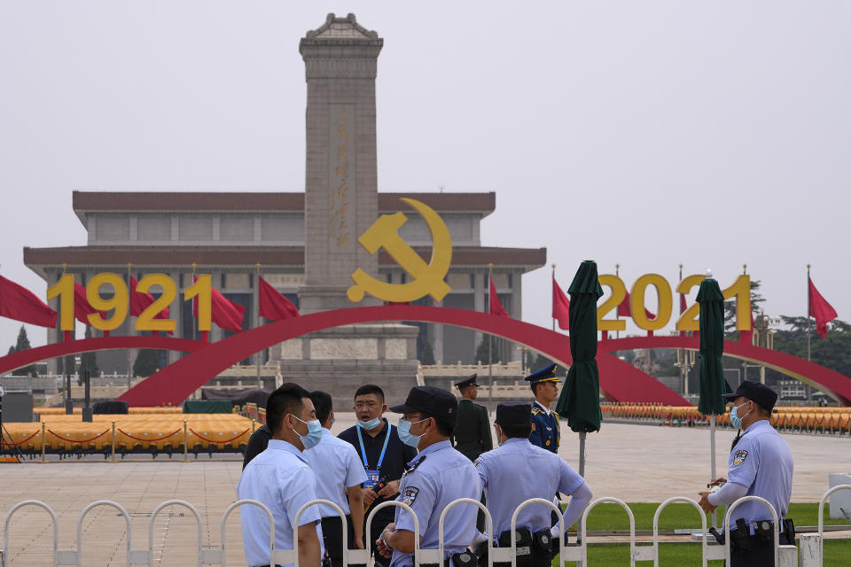Police chat with each other as they gather near a platform with a Communist Party's logo setup on Tiananmen Square in Beijing, Monday, June 28, 2021. China is marking the centenary of its ruling Communist Party this week by heralding what it says is its growing influence abroad, along with success in battling corruption at home. (AP Photo/Andy Wong)