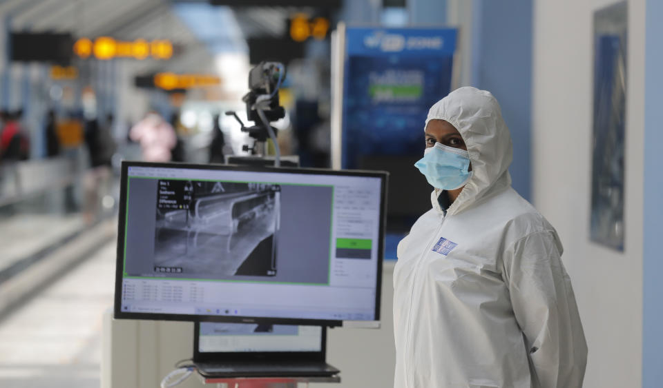 A Sri Lankan airport worker stands next to a thermal scanner inside a terminal at the Katunayake International Airport in Colombo, Sri Lanka, Wednesday, Jan. 20, 2021. Sri Lanka's tourism minister said that the airports in the country will be reopened for tourists according to health guidelines from Jan.21. (AP Photo/Eranga Jayawardena)