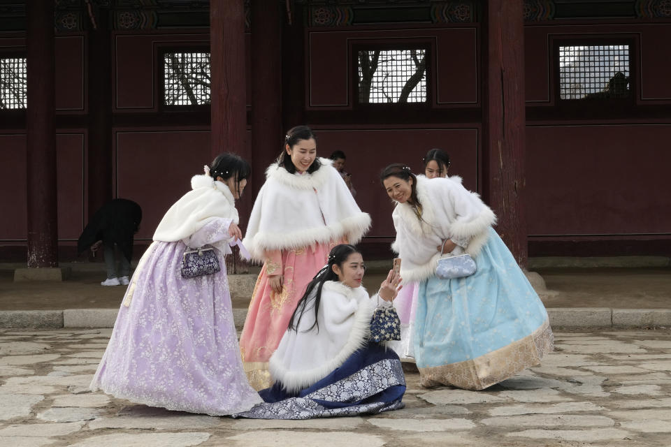 Gente con el tradicional traje hanbok mira un celular durante su visita para celebrar el Año Nuevo Lunar al Palacio de Gyeongbok, que fue el principal palacio real de la Dinastía Joseon y uno de los monumentos más conocidos de Corea del Sur, en Seúl, Corea del Sur, el domingo 22 de enero de 2023. (AP Foto/Ahn Young-joon)