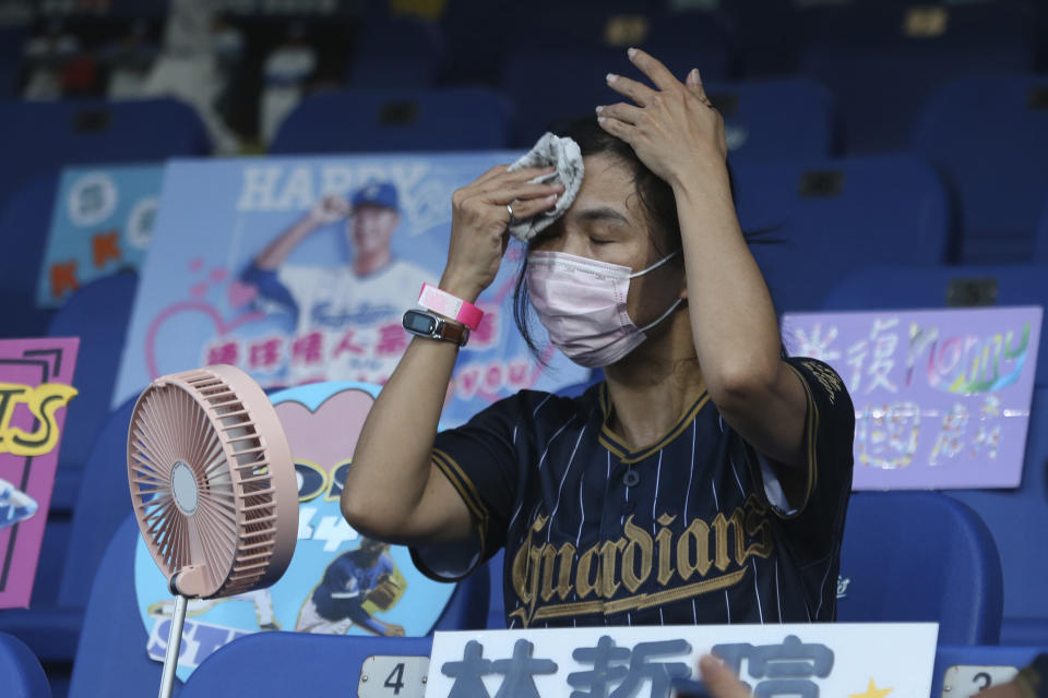 FILE - In this May 8, 2020, file photo, a fan tries to cool off at Xinzhuang Baseball Stadium in New Taipei City, Taiwan. The Taiwan baseball league is continuing as a trailblazer for sports resuming after the lockdown in the coronavirus pandemic. An easing of restrictions by the government on Sunday, June 7, 2020 allows more fans at the ballparks and allows them to sit closer together while they’re supporting their teams in the Taiwan-based CPBL. Fans are only required to wear face masks when they're not in their seats and ball parks are allowed to be up to 50% capacity. (AP Photo/Chiang Ying-ying, File)