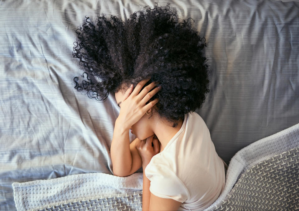 a person lying in bed cover their face with their hand